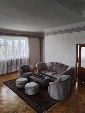 Una sala de estar con un sofá gris, otomanas y una mesa de centro.