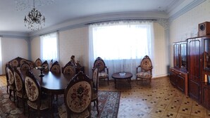 A dining room with a round table, chairs, a chandelier, and a cabinet with glass doors. - Airport to Echmiadzin Guest House (Parakar)