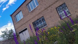 A two-story brick building with three windows, one of which has decorative metal bars. - Airport to Echmiadzin Guest House (Parakar)