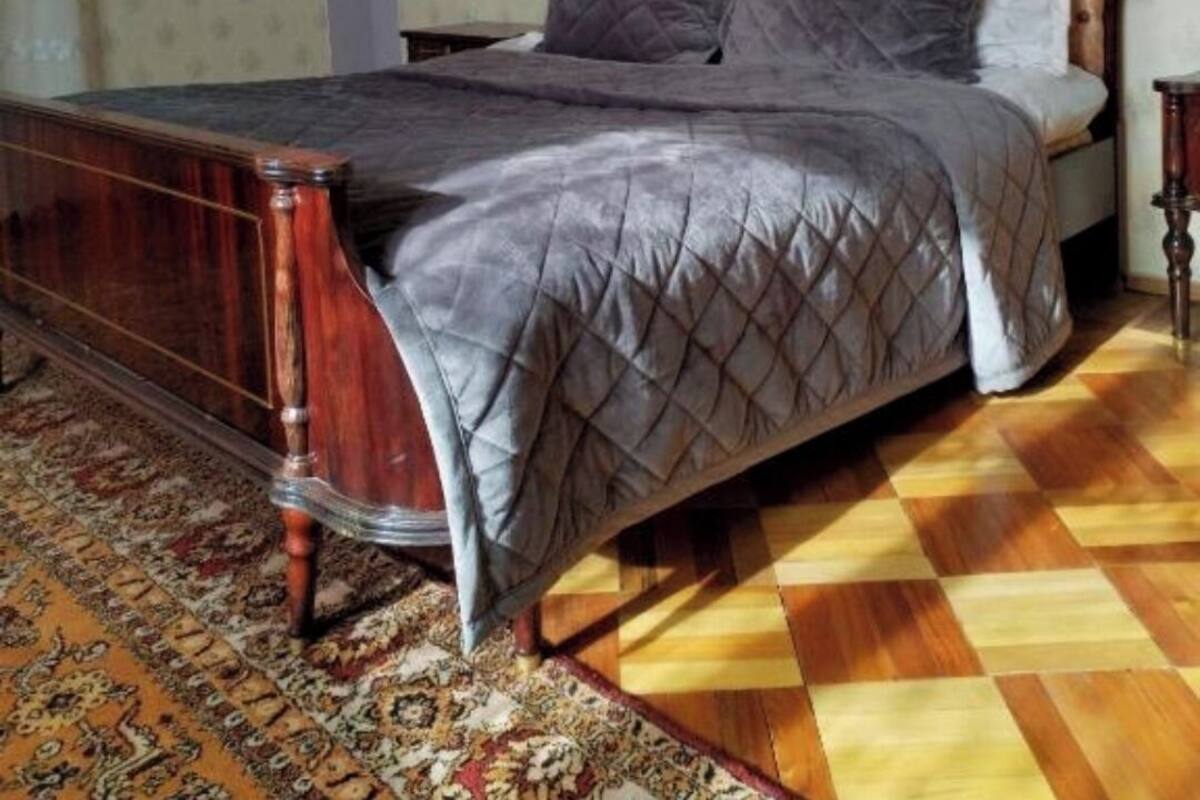 Un dormitorio con estructura de cama de madera, pared con diseño y suelo a cuadros.