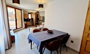 A modern kitchen with wooden cabinets, a dining table with chairs, and a view of the outside through large windows. - 50m from ski slopes, 1st floor, balcony, tv, 57m², Montalbert (La Plagne)