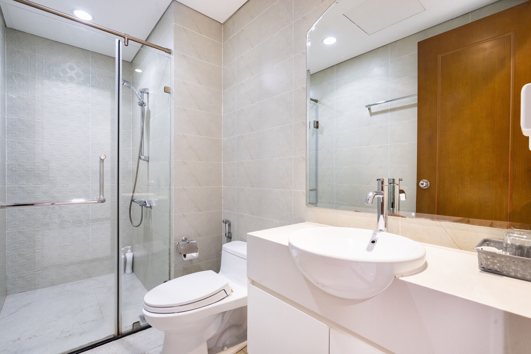 A modern bathroom with a glass-enclosed shower, a white toilet, and a vanity with a sink.