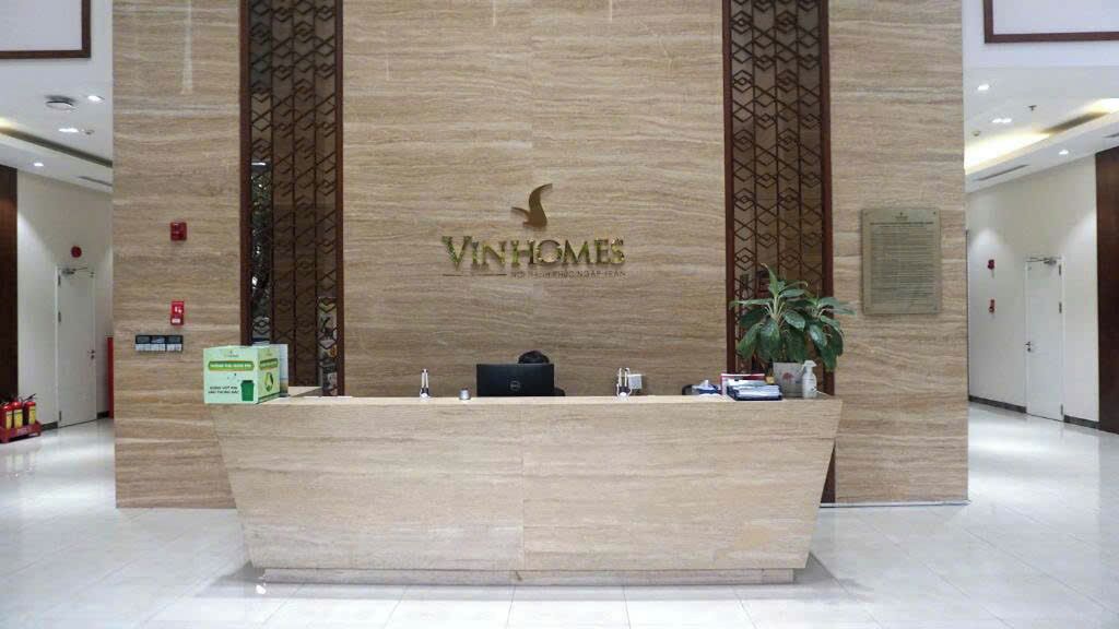 A reception desk with a logo, a potted plant, and a fire extinguisher.