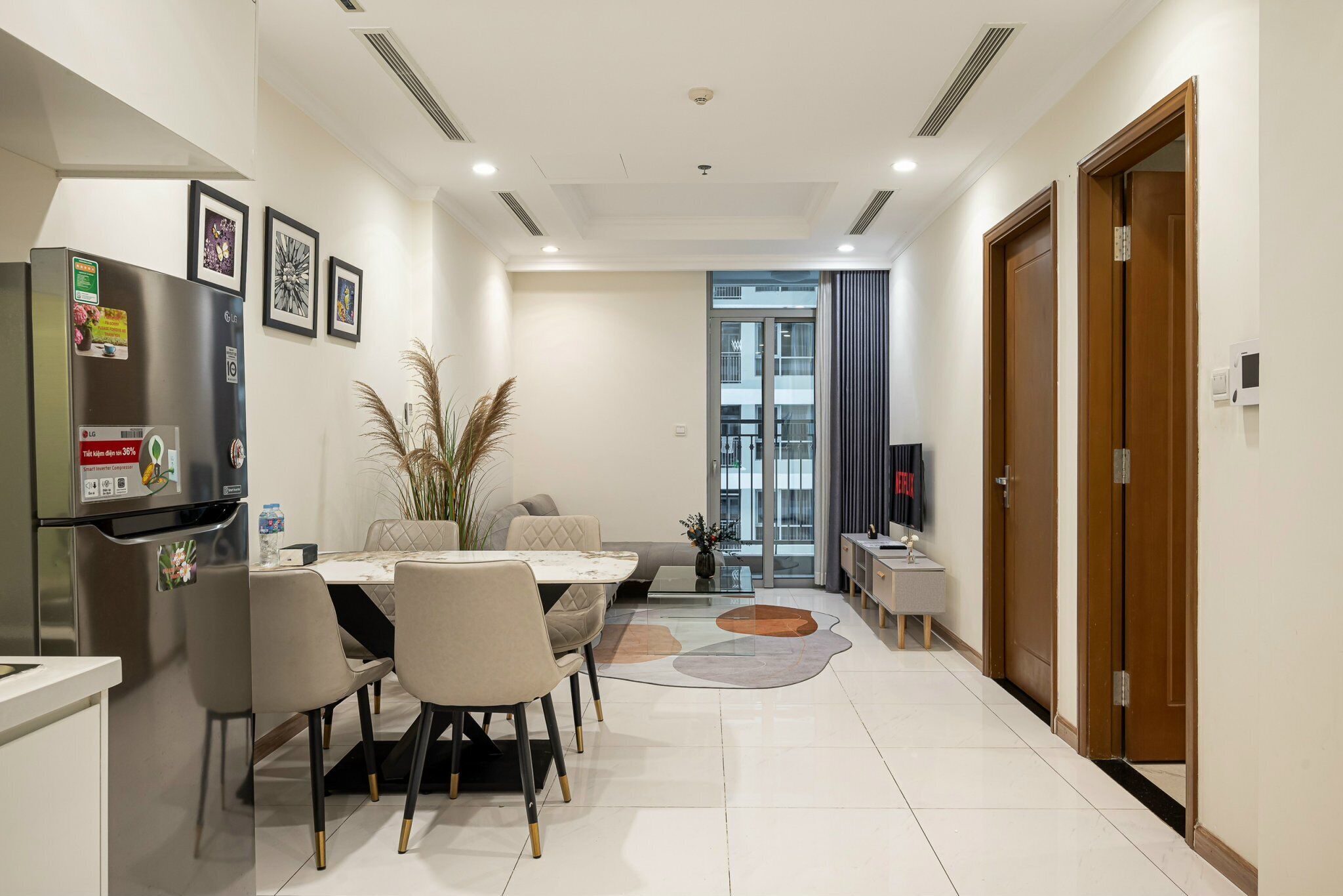A modern dining area with a table, chairs, and a refrigerator.