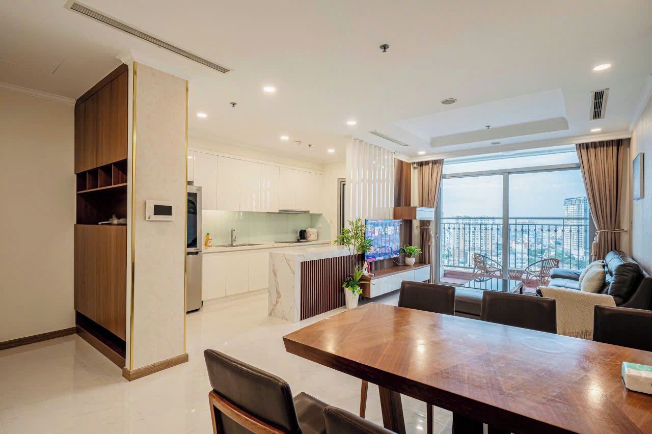 A modern living room with a dining area, a kitchen, and a balcony with a city view.