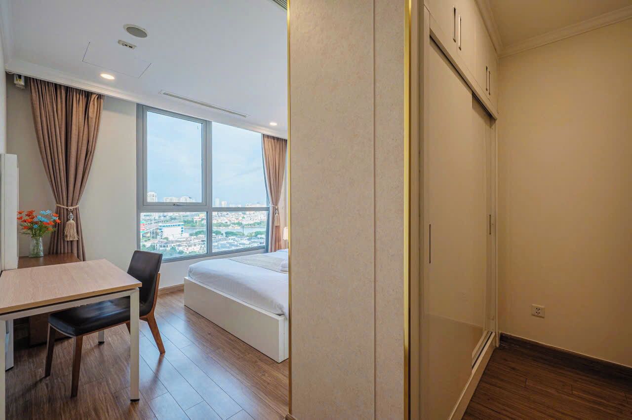 Una camera d'albergo moderna con un'ampia finestra, un letto, una scrivania e una sedia.