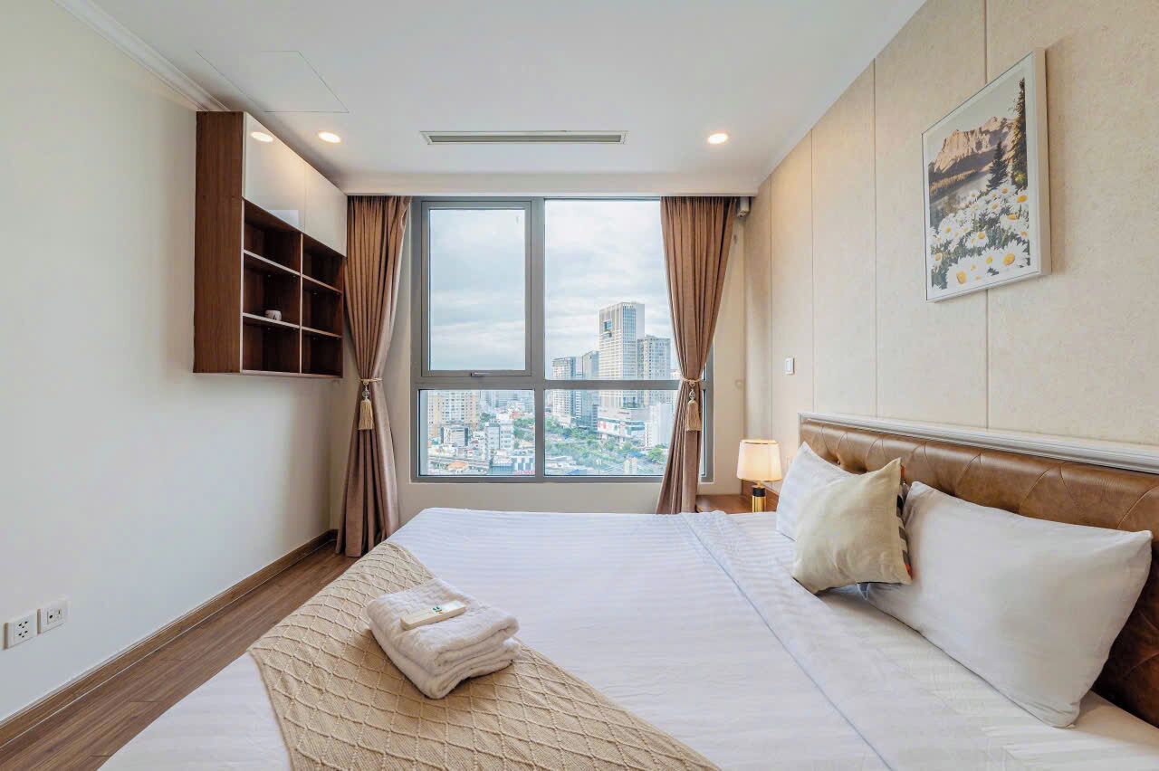 Ein Hotelzimmer mit einem großen Bett, Blick auf die Stadt, einer Wandregal und einem Gemälde an der Wand.