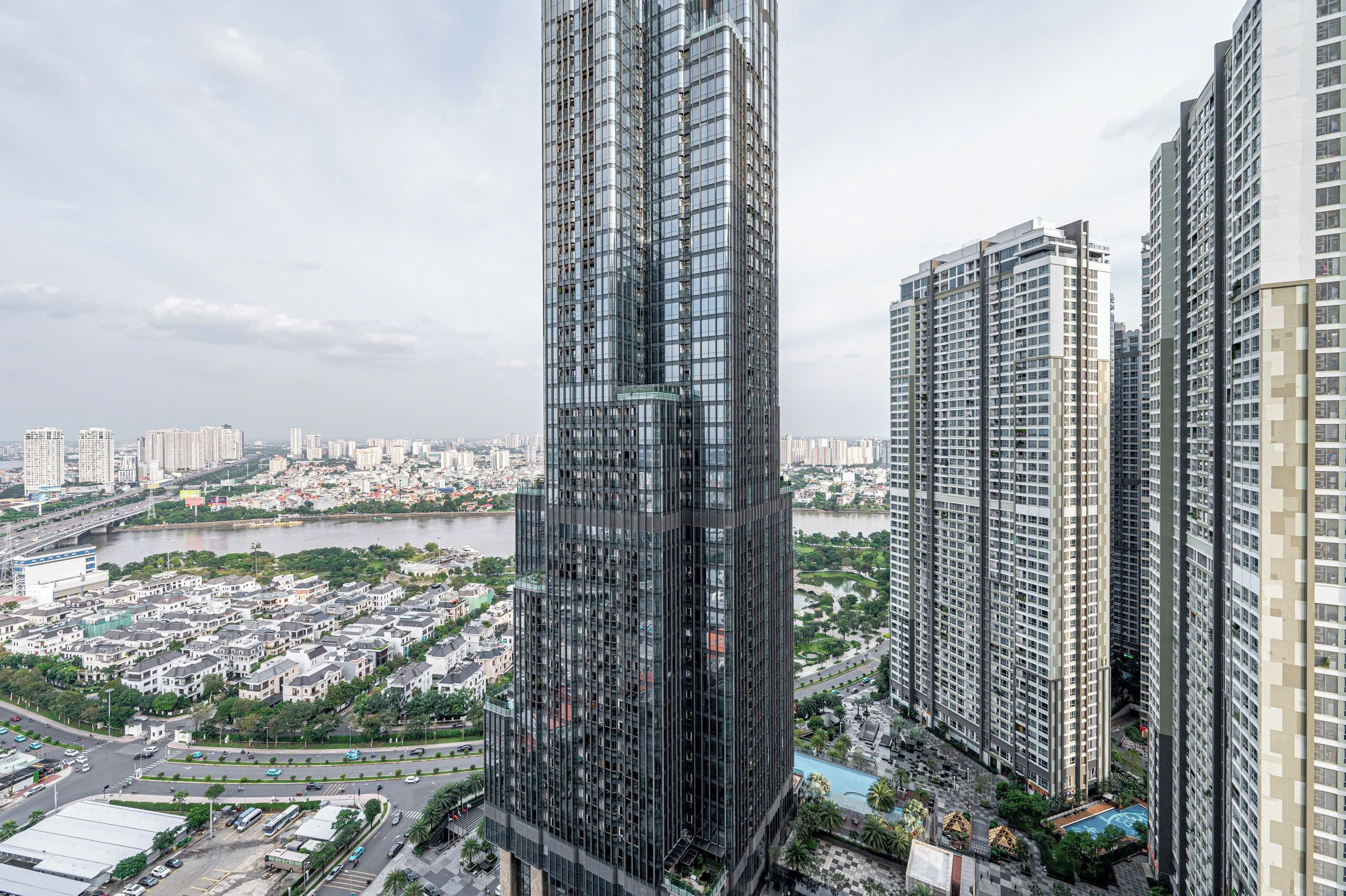 A high-rise building with a modern glass facade, surrounded by other tall buildings and a river in the background.