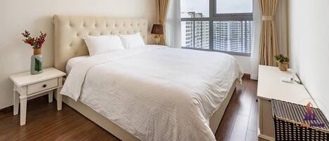 Un dormitorio con una cama grande, una mesita de noche, un escritorio y una ventana con cortinas.