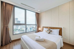 A hotel room with a large window, a bed with white bedding, a headboard, and a city view. - Cityhome Apartment Vinhomes Central Park (Ho Chi Minh City)