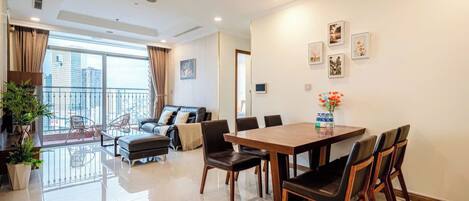 A modern living room with a dining area, large windows, and a balcony.