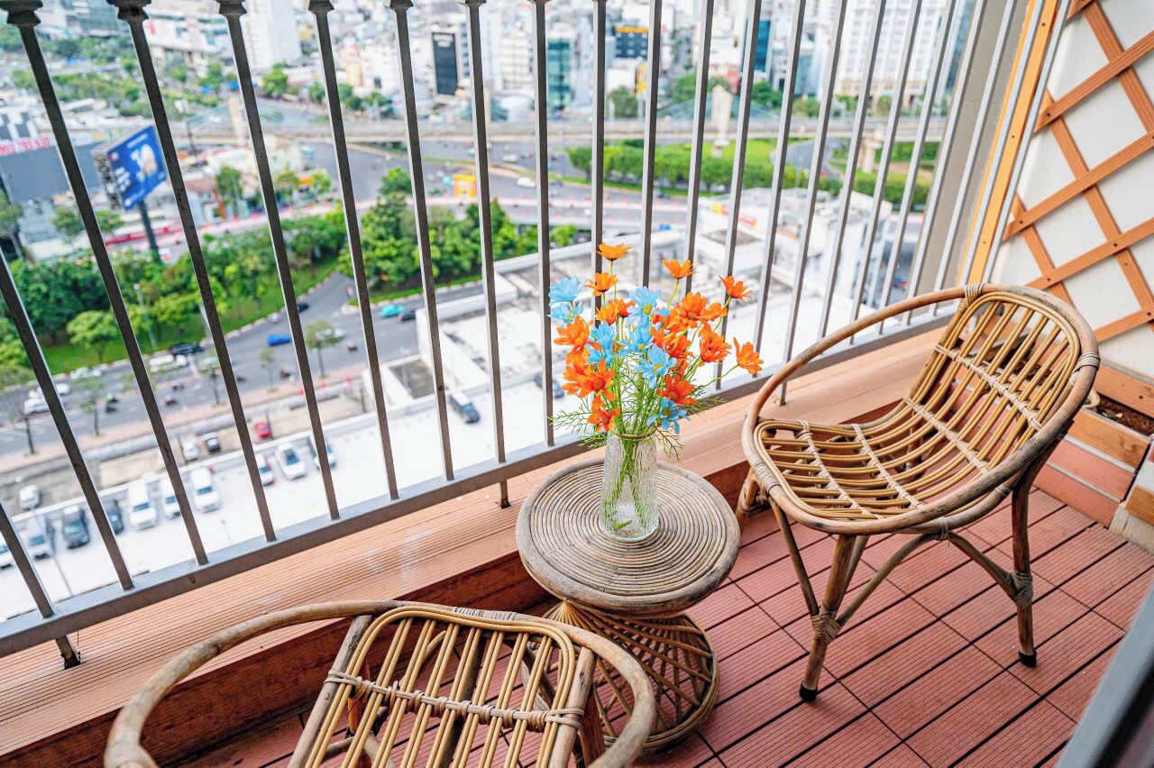 A balcony with wicker chairs, a small round table, and a vase with flowers.