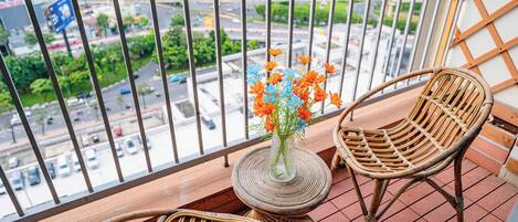 A balcony with wicker chairs, a small round table, and a vase with flowers.