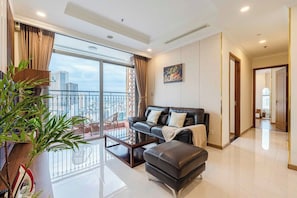 A modern living room with a balcony, a sofa, a coffee table, and a potted plant. - Cityhome Apartment Vinhomes Central Park (Ho Chi Minh City)