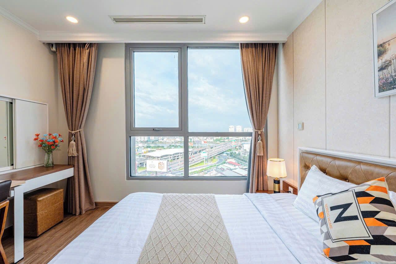 A hotel room with a bed, a desk, a chair, a lamp, and a window with a city view.