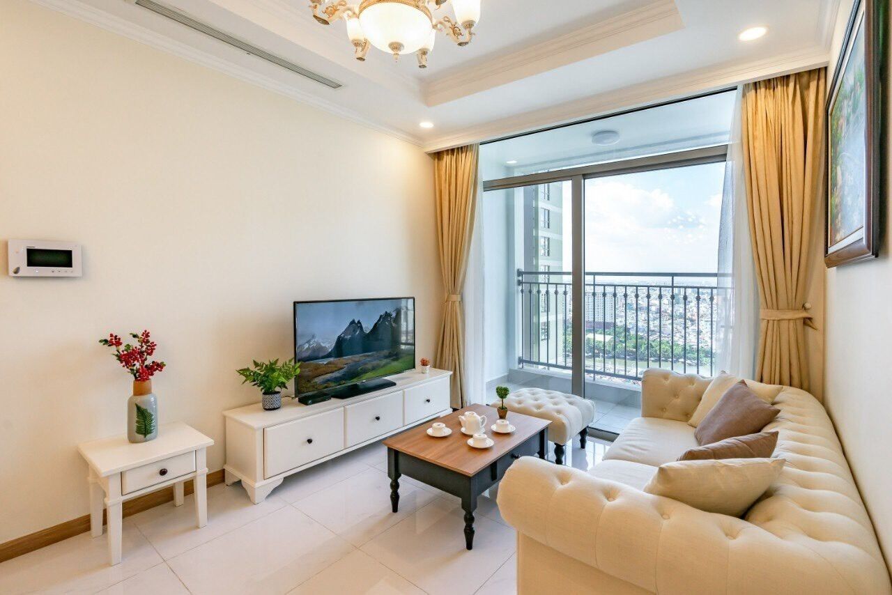 Una sala de estar moderna con un televisor de pantalla plana, un sofá, una mesita de centro y una mesita auxiliar con objetos decorativos.