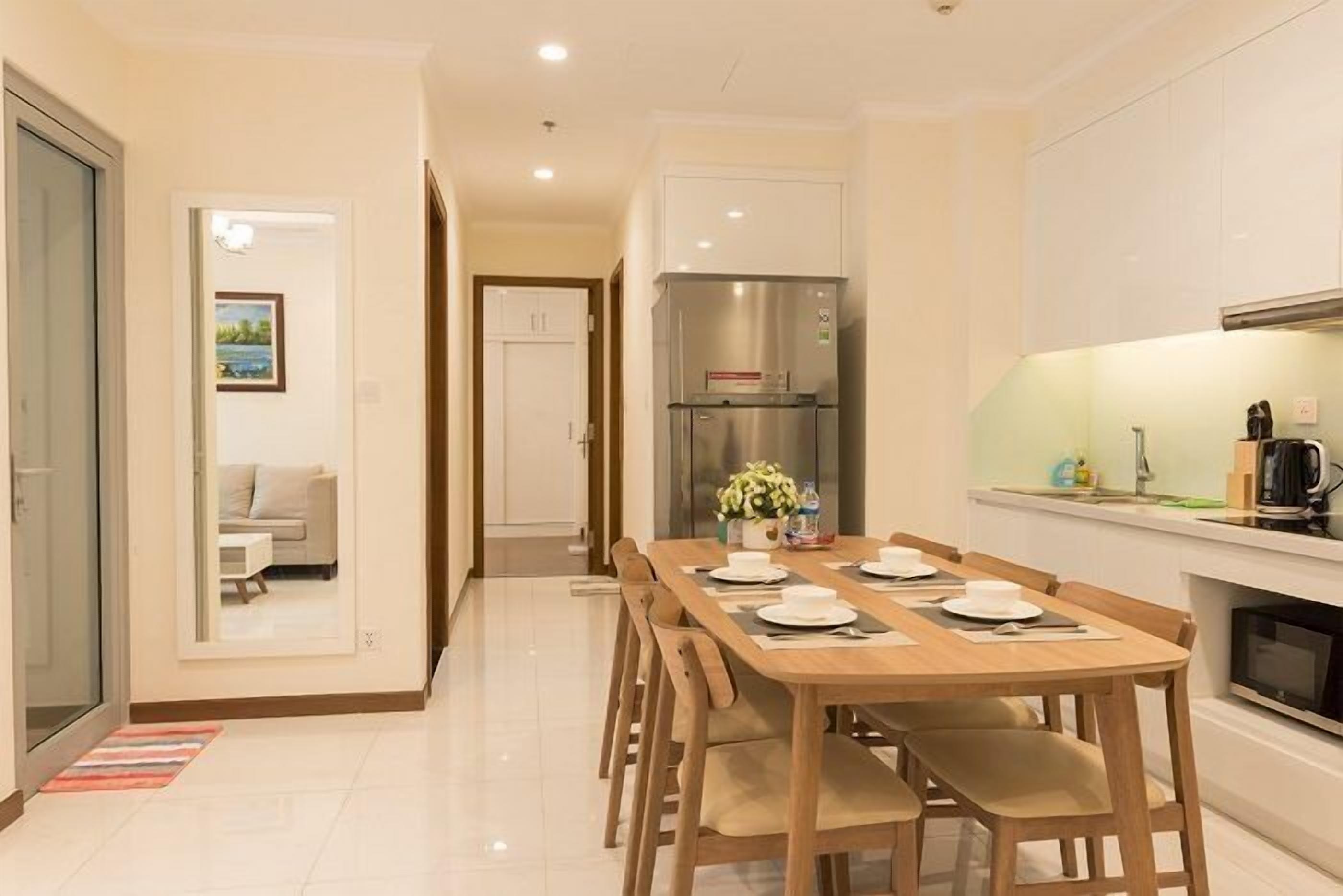 A modern kitchen with a dining area, featuring a stainless steel refrigerator, a built-in oven, and a dining table set for four.