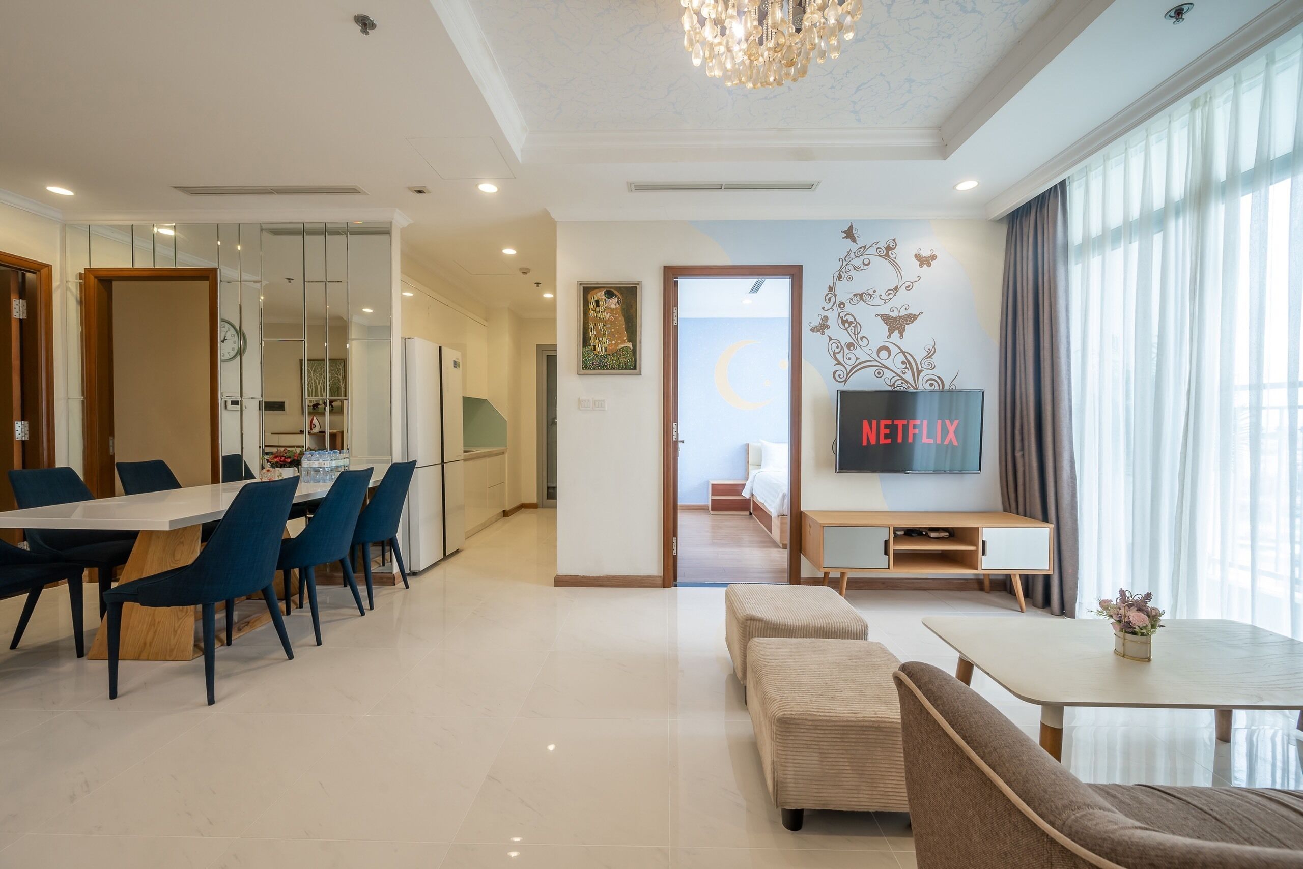 A modern living room with a dining area, a TV, and a view of the outside.
