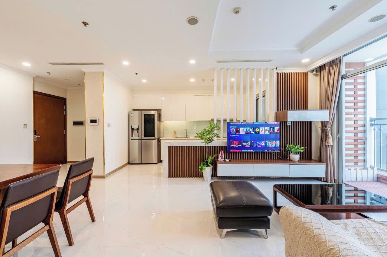 A modern living room with a dining area, a kitchen, and a TV.