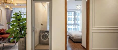A hotel room with a washing machine, a bed, and a view of the city.