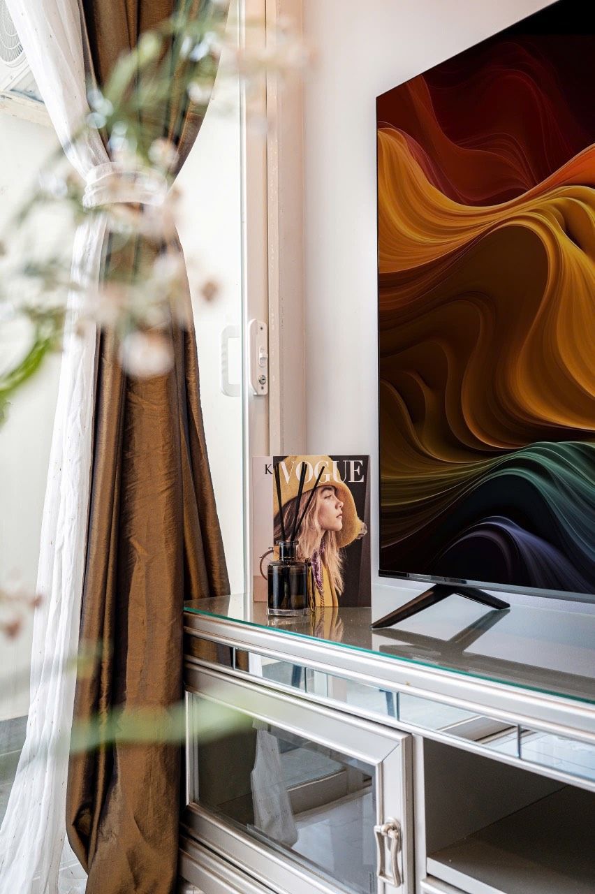 Une chambre moderne avec un grand téléviseur à écran plat fixé au mur, une vitrine en dessous et un magazine posé sur la vitrine.