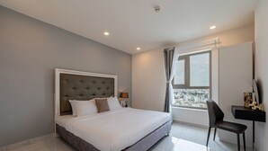 Een moderne slaapkamer met een groot bed, een bureau met stoel en een raam met uitzicht over de stad.
