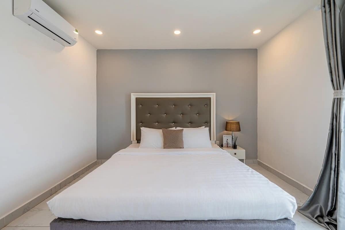 Cama bem arrumada com cabeceira estofada em quarto de hotel.