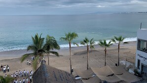Une plage avec des palmiers, un bâtiment portant l’inscription « Mango », et un groupe de personnes sur le sable.
