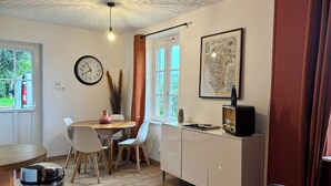 A compact living space with a dining area, kitchenette, and a large window. - L'escale de Saint Martin (Saint-Martin-de-Mailloc)