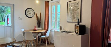 A compact living space with a dining area, kitchenette, and a large window.