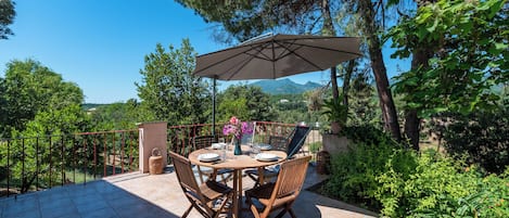 An outdoor patio with a round table, chairs, and a large umbrella.