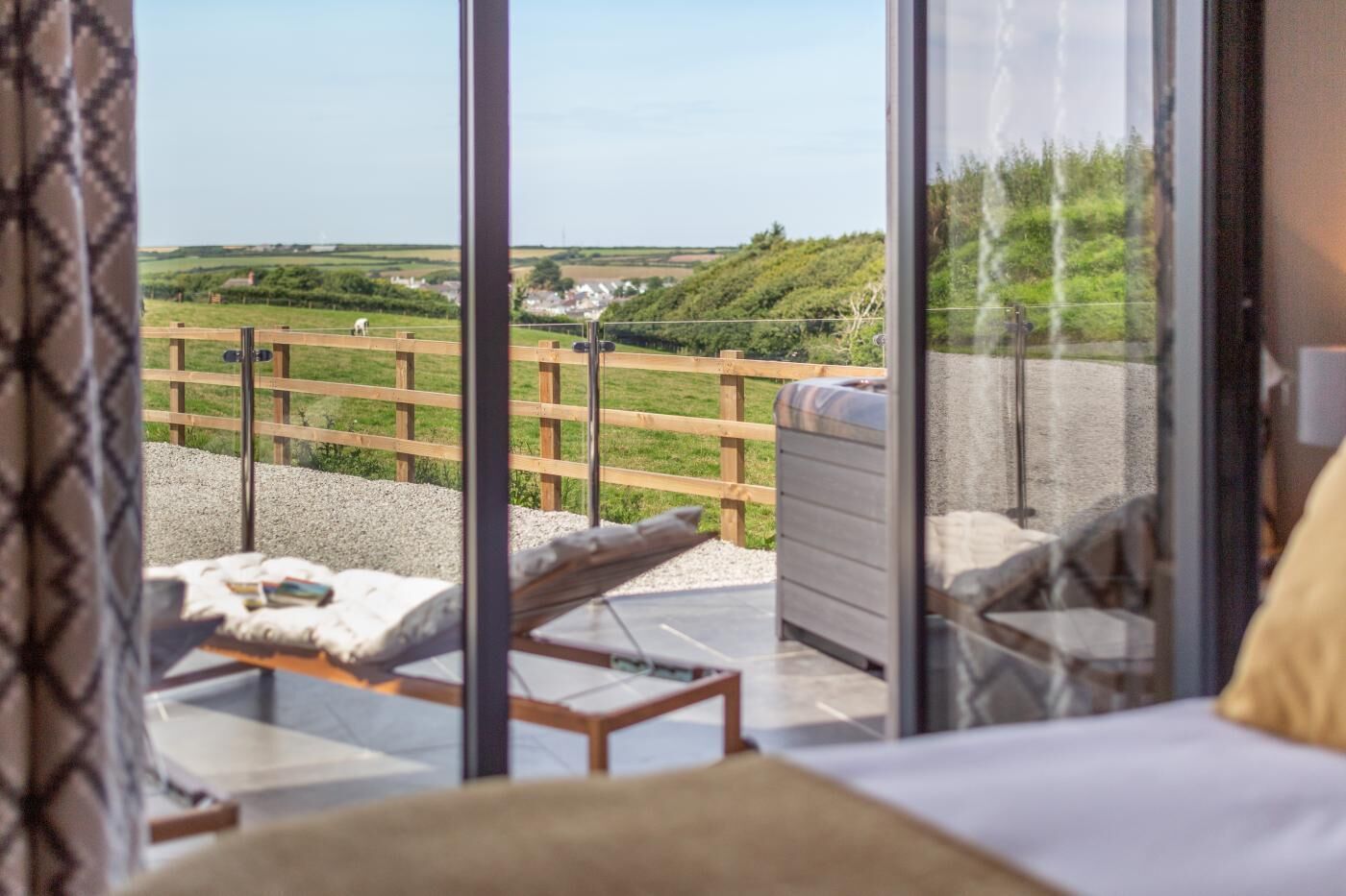 A bedroom with a large window overlooking a grassy area and a wooden fence.