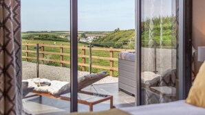 A bedroom with a large window overlooking a grassy area and a wooden fence. - 3 Bed in Hartland (oc-w29797) (Hartland)