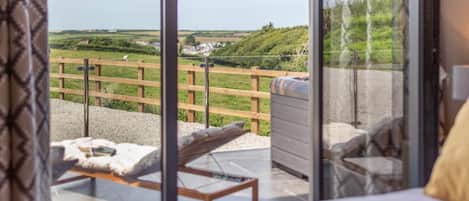 A bedroom with a large window overlooking a grassy area and a wooden fence.