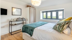 Una camera da letto con un letto, un comodino, uno specchio, una finestra e una lampada a soffitto.