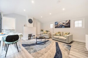 Ein modernes Wohnzimmer mit einer Couch, einem Couchtisch und einem Essbereich mit Tisch und Stühlen.