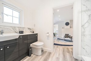 Een moderne badkamer met een marmeren wastafel, donkere kastjes en een toilet.