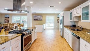 A spacious kitchen with a central island, stainless steel appliances, and a view to the dining area. - Charming 3-bed, 2- bath house with open concept living and sunroom in Savannah (Savannah)
