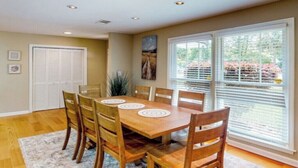 A dining area with a wooden table and chairs, a white rug, and a window with blinds. - Charming 3-bed, 2- bath house with open concept living and sunroom in Savannah (Savannah)