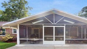 A modern house with a covered patio area featuring a dining table and chairs. - Charming 3-bed, 2- bath house with open concept living and sunroom in Savannah (Savannah)