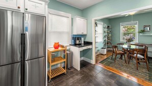 A modern kitchen with stainless steel appliances, a built-in coffee maker, and a dining area with wooden chairs and a glass table. - Charming 2 BR house in Old Hickory Village, a short walk from the lake road  (Nashville)