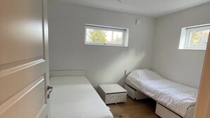 Een kleine, compacte kamer met twee bedden, een tafeltje en een raam.