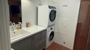 Een kleine wasruimte met een wasmachine, een droger en een wasbak.
