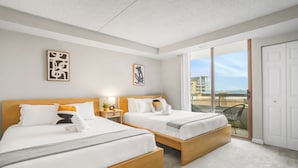 Ein Hotelzimmer mit zwei Betten, einem Balkon mit Blick und Bildern an den Wänden.