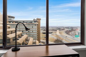 Escritorio con una lámpara y vista panorámica de la ciudad a través de amplios ventanales.