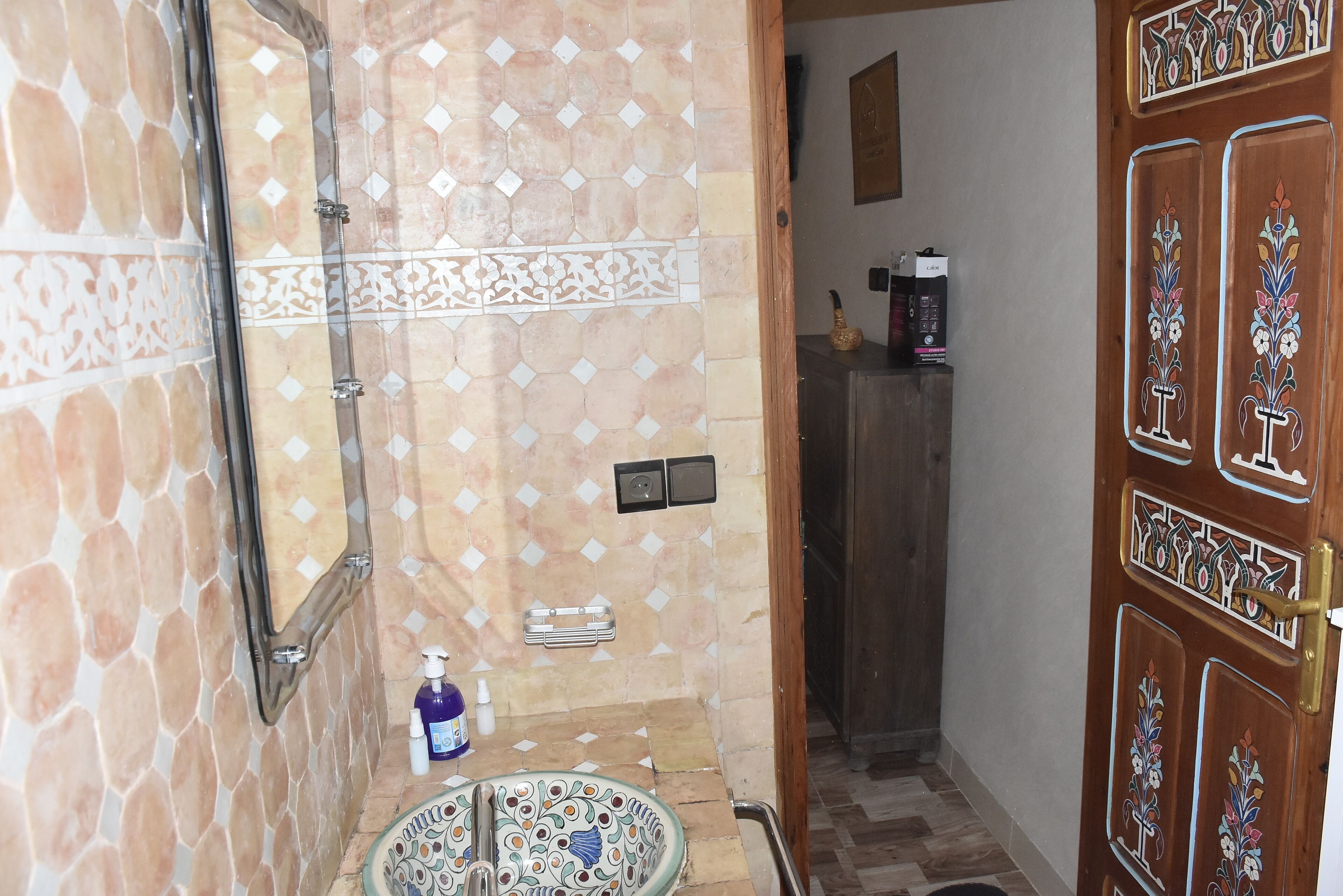 Une salle de bain avec un mur carrelé, un lavabo et une douche.