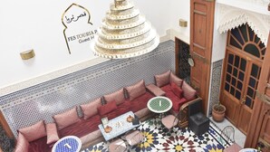 A Moroccan-style interior with a patterned sofa, a decorative chandelier, and a wall-mounted sign reading "FEST TOURIST Guest". - Fes Touria Palace (Fes)
