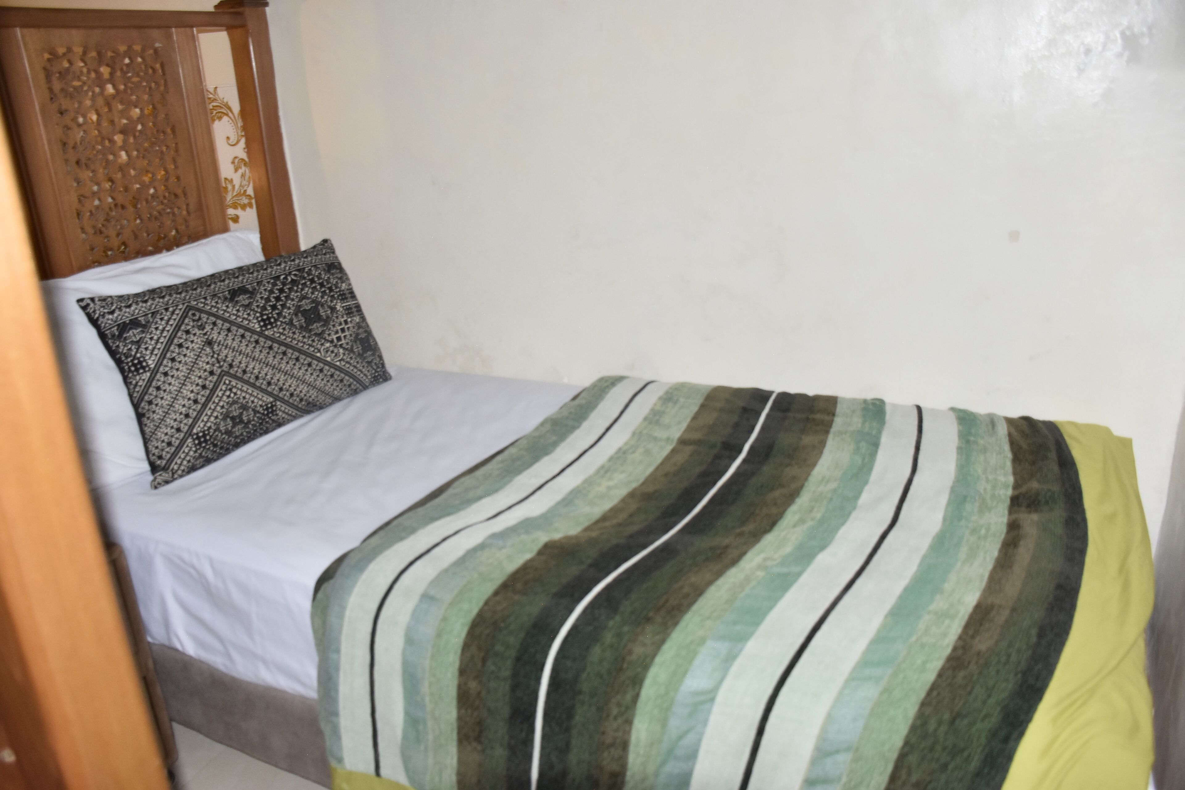 Uma cama de solteiro com travesseiro estampado e cobertor listrado.