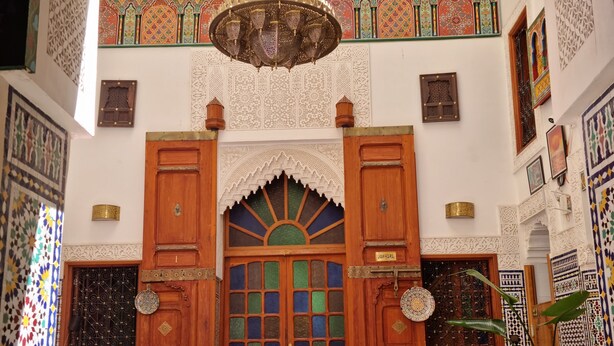 A traditional interior with ornate wooden doors, a chandelier, and detailed wall patterns. - Fes Touria Palace (Fes)