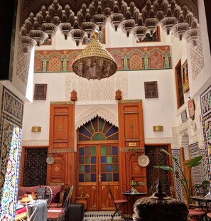 A traditional interior with ornate wooden doors, a chandelier, and detailed wall patterns. - Fes Touria Palace (Fes)